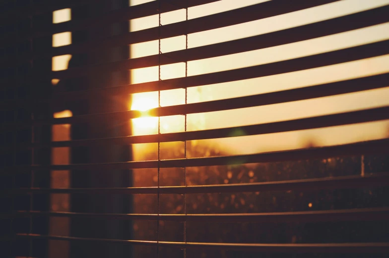 the sun is shining through blinds outside a window