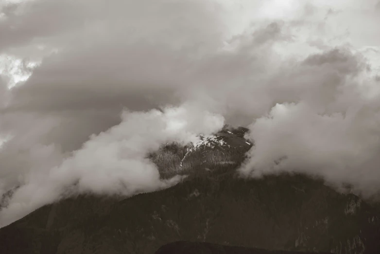 a mountain covered in clouds with a boat traveling on it