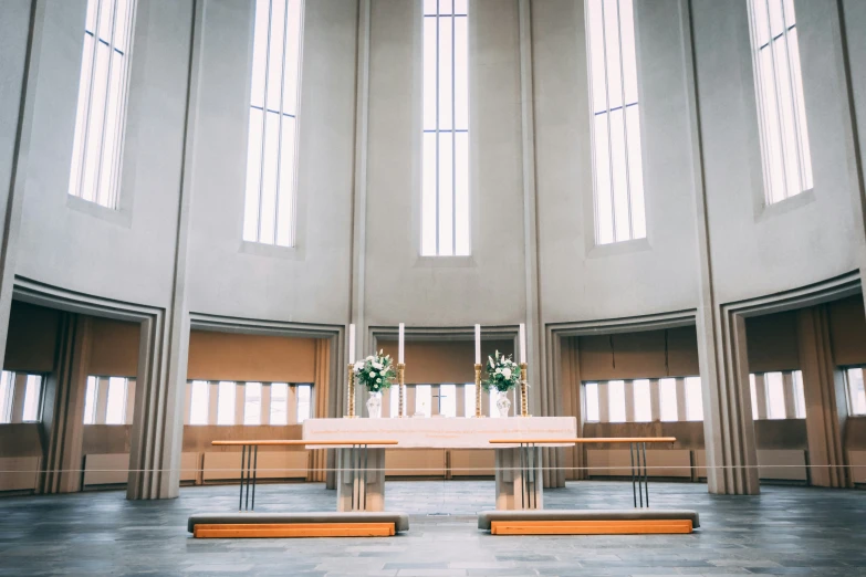 an empty church has windows and two vases with flowers