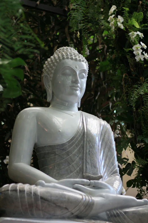 a statue of a person sitting down by some bushes