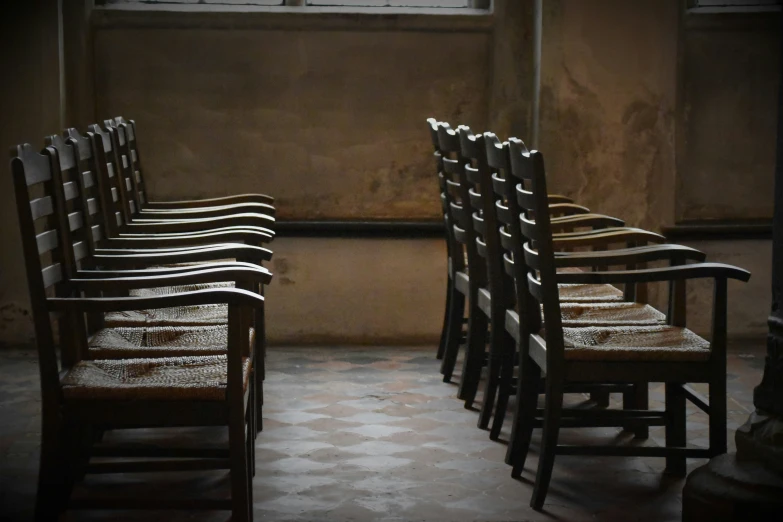 a row of chairs standing up against a wall with their backs turned towards the light