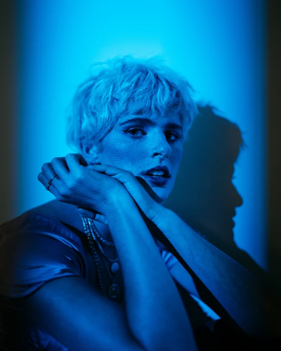 a woman with blue light on her face posing for a portrait