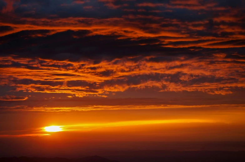 the setting sun shining red through the clouds