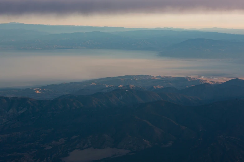 an airplane wing flies over the mountains and hills