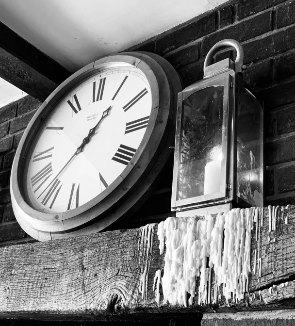 a clock with an outside lantern sitting on the side of a wall