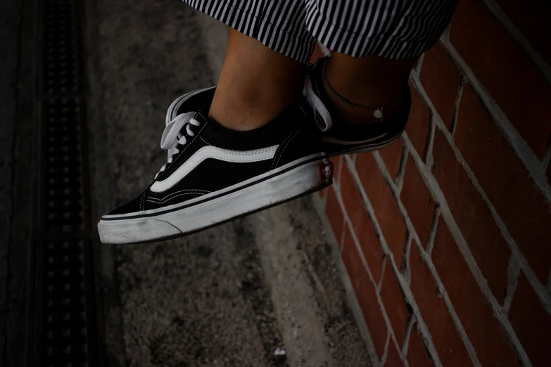 a person in black and white striped pants standing by brick wall