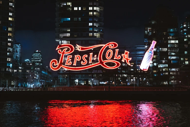 the word pepsi on a lighted sign in front of a large city at night