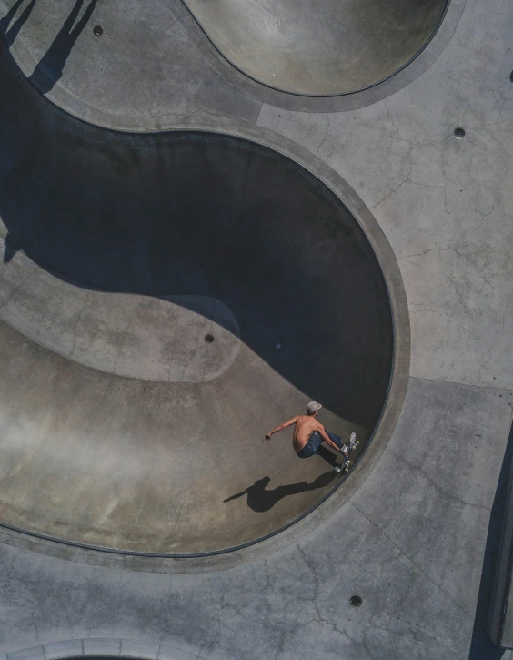 a skateboarder in a gray shirt riding on cement in a skate park