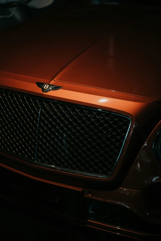 a close up of the front of a shiny orange mercedes