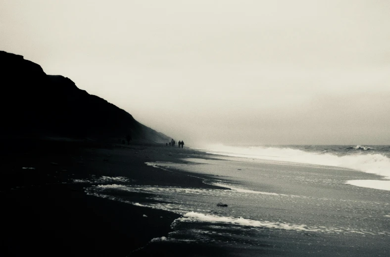 a foggy black and white po of people at the ocean