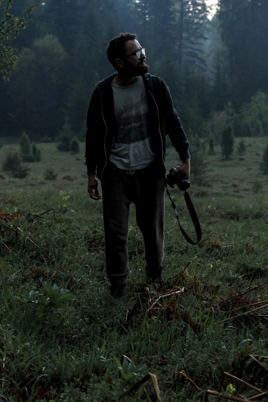 man walking through forest holding a camera in his hand