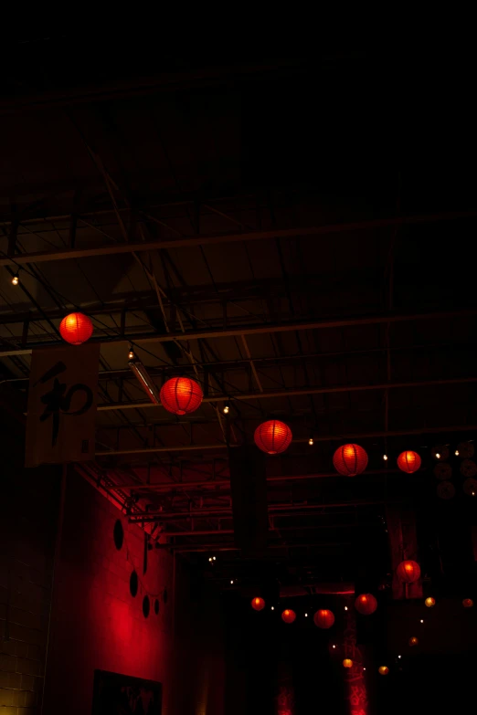 many lights inside a dark room that is lit up with red lanterns