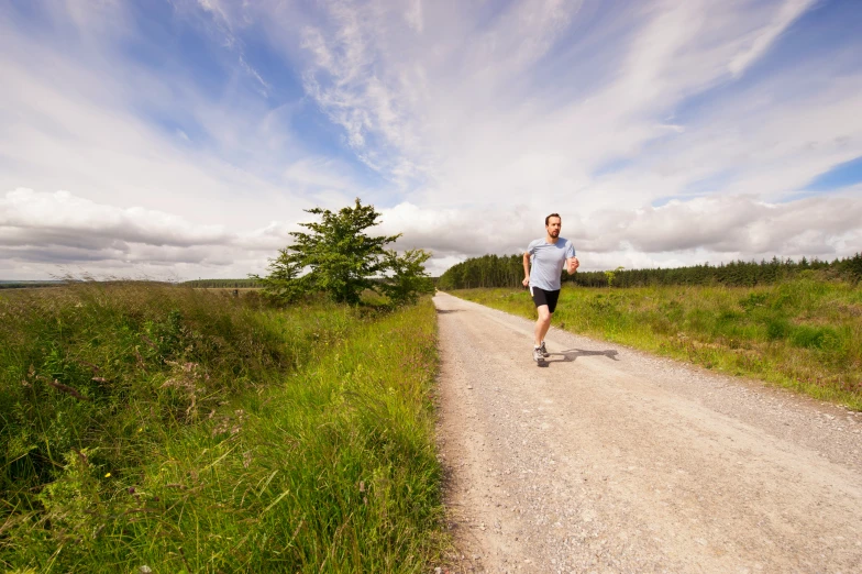 man jogging on dirt trail in open field