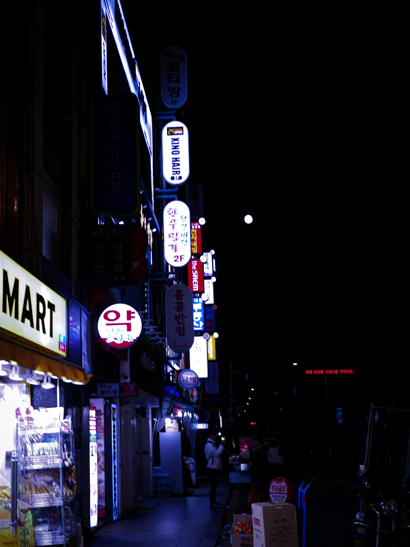 a city street with some signs lit up at night