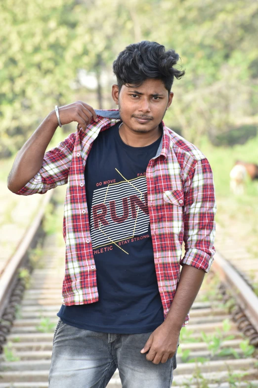 a young man is standing in front of railroad tracks