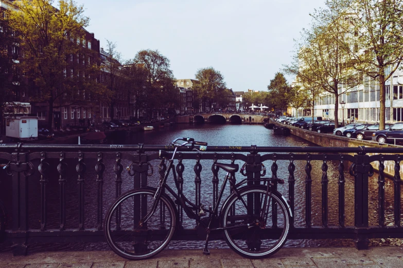 a bicycle resting on the rail by a canal
