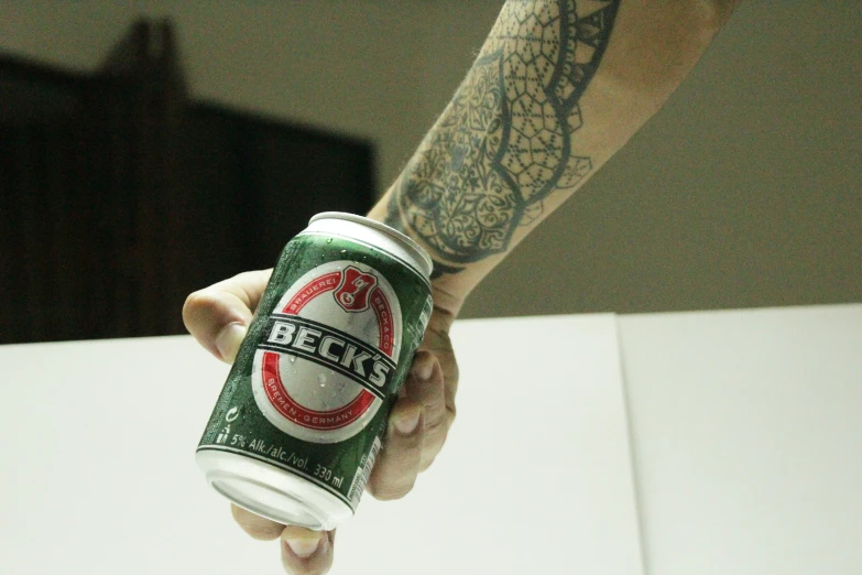 an arm holding a can of beer, which has a lizard on it