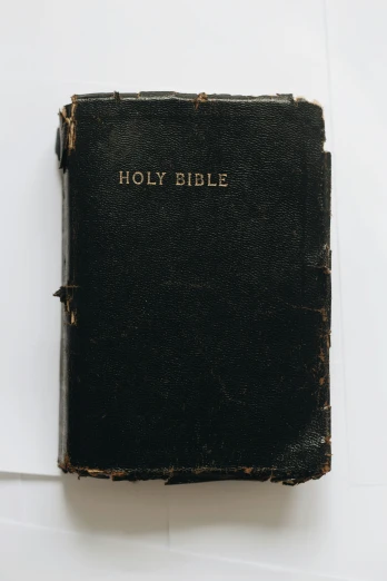 a very old black bible that is sitting on a table