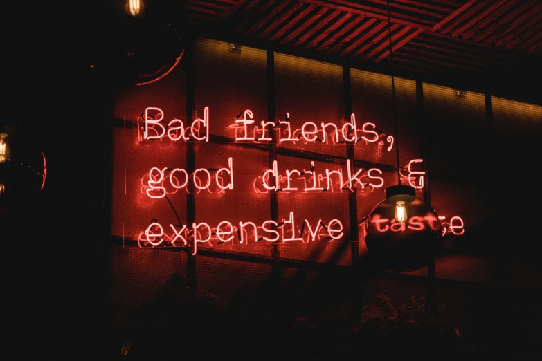 red neon sign that says, bad friends, good drinks and expensive parts