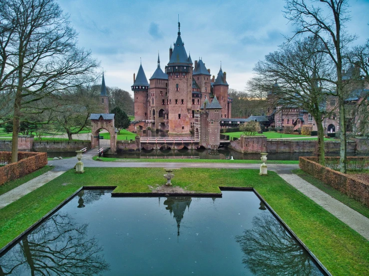 an outdoor pond sits in front of the large brick castle