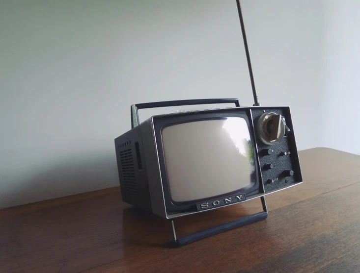 a small tv is placed on top of a wood desk