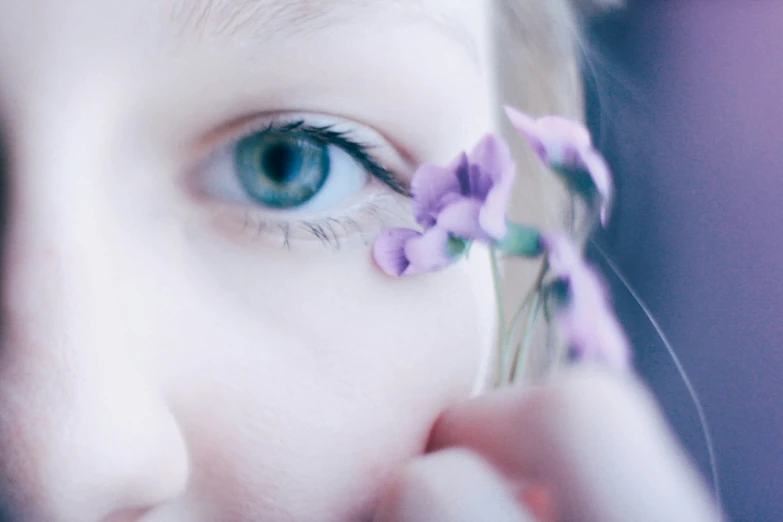 a girl with blue eyes holds a tiny flower