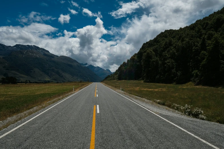 an empty road is next to the mountains