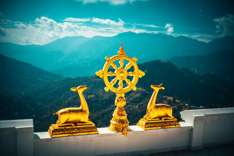 golden giraffe statues on top of a building with mountains behind them