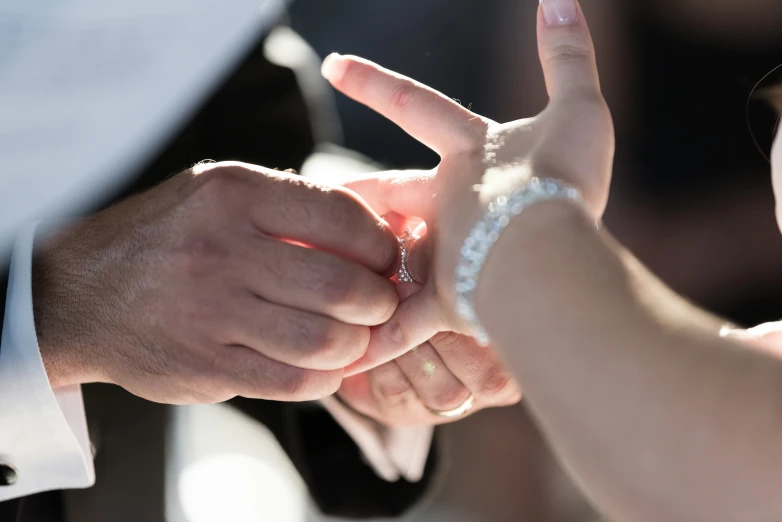 a bride and groom putting their wedding ring on the finger of their partner