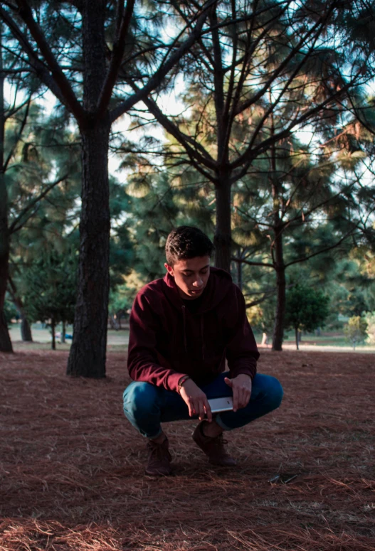 a person kneeling down near some trees holding soing