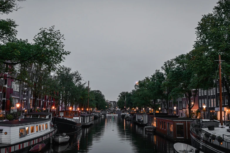 boats floating along a canal at dusk in a city