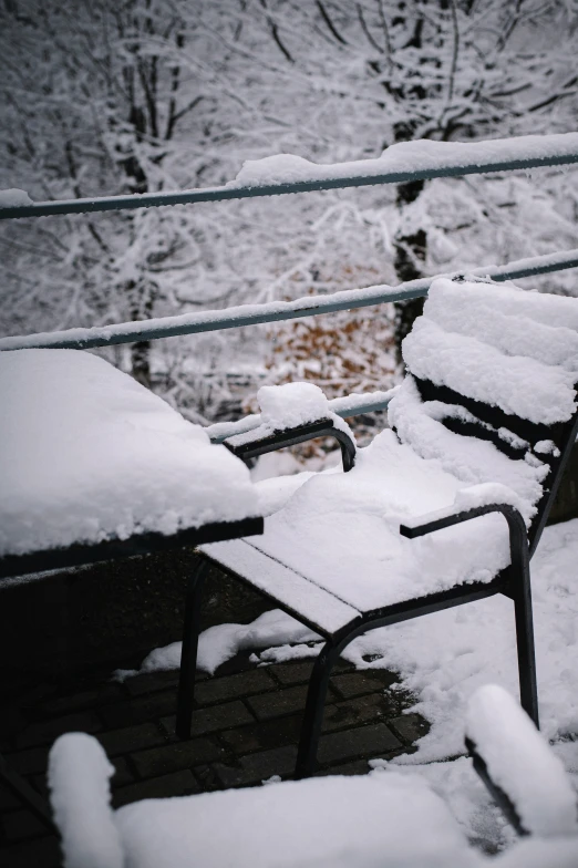 two park benches covered with snow in winter