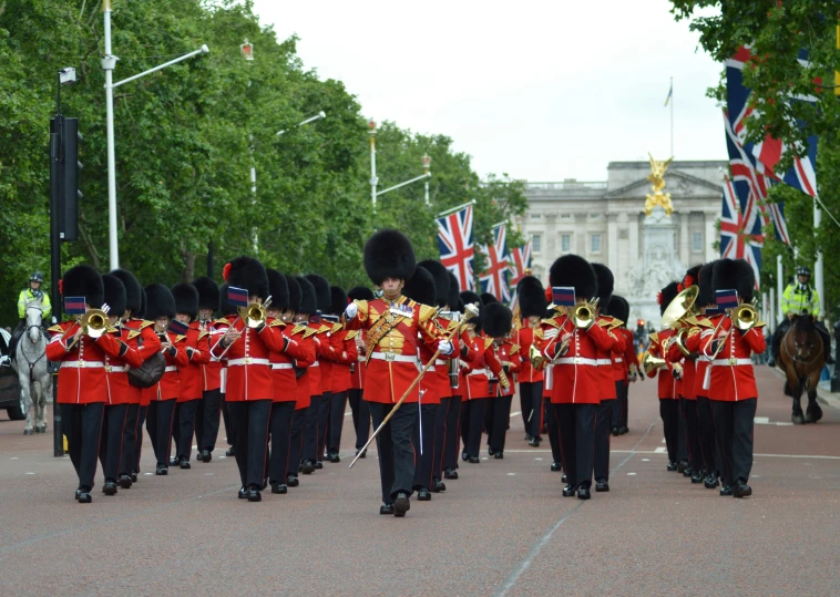 the british military band, including members in red uniform, march down the street