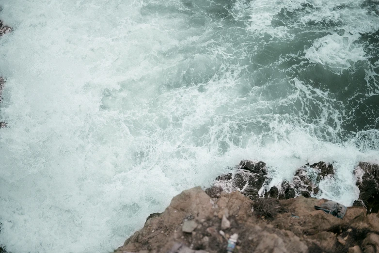 a body of water that is crashing over a rock