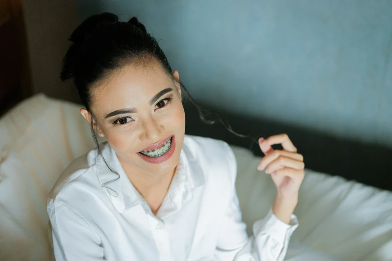 woman in white shirt with metal teeth sitting on a couch