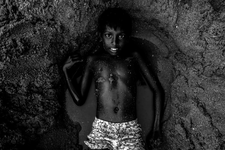 a black boy with short shorts standing in water