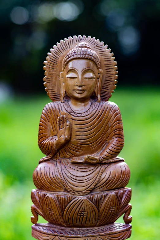 a small buddha statue sitting in the middle of a grassy field