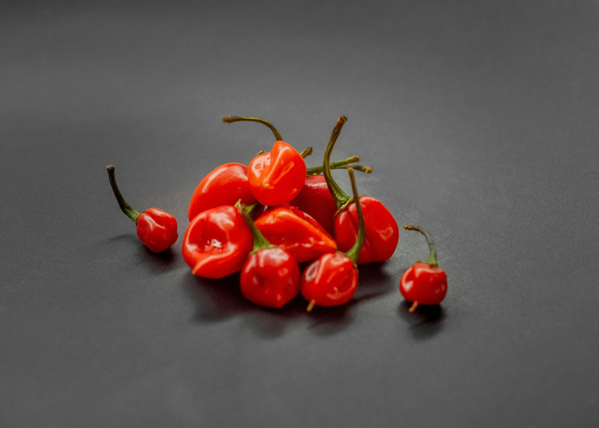 several small red bell peppers on a black surface