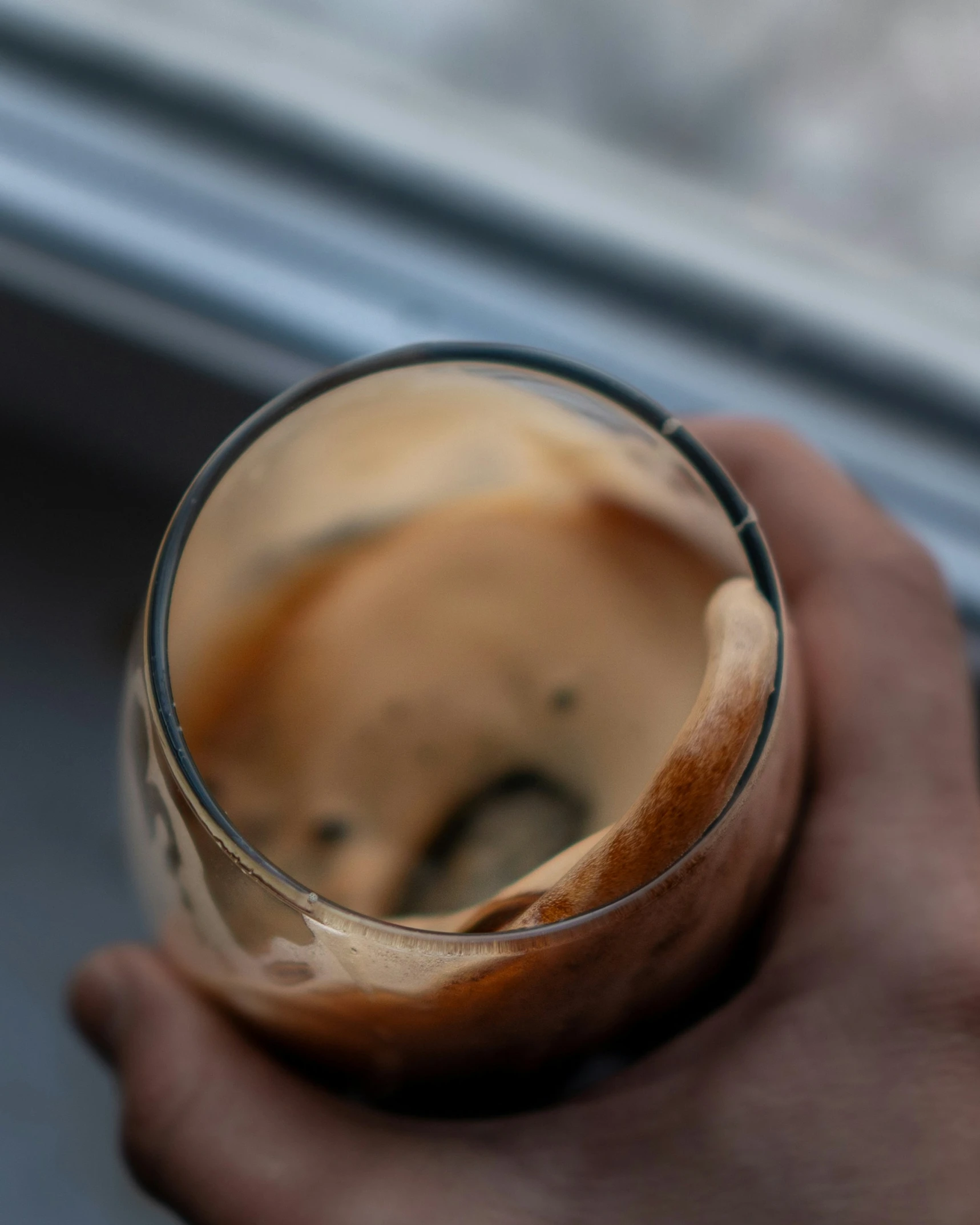 someone holding their drink in a glass near a window