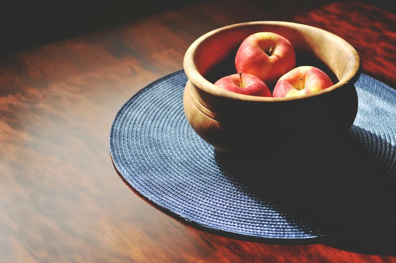 there are three apples in the bowl that is on top of a table