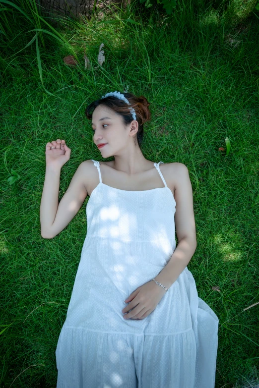 a girl wearing white is laying in the grass