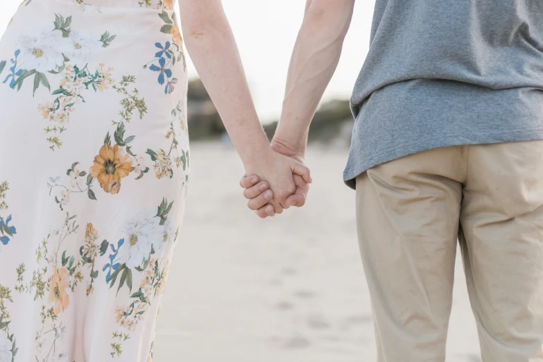 a couple holding hands walking through a beach