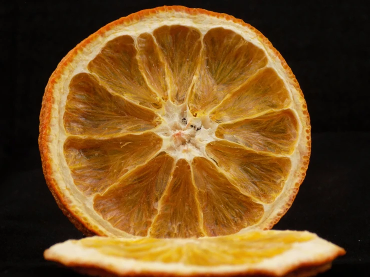 a cut up orange is displayed on the black surface