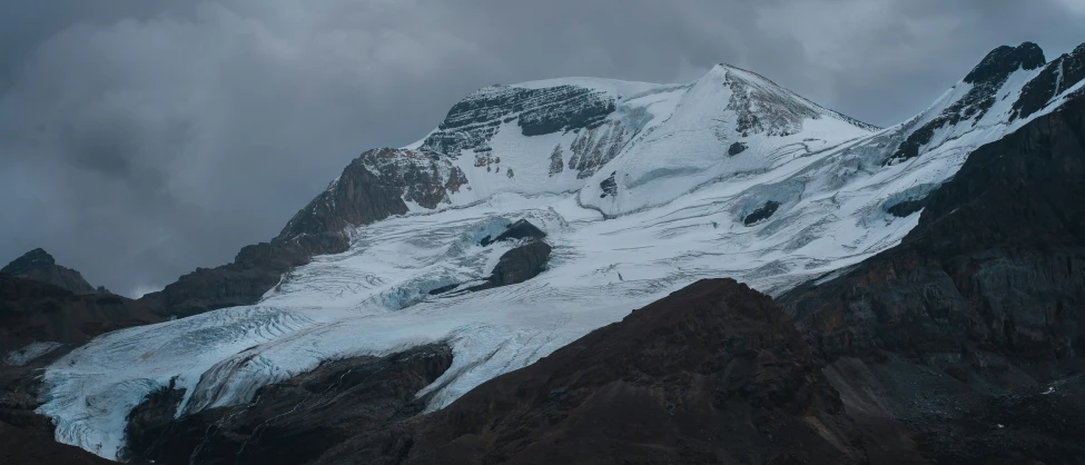 a large snowy mountain covered in snow under a cloudy sky