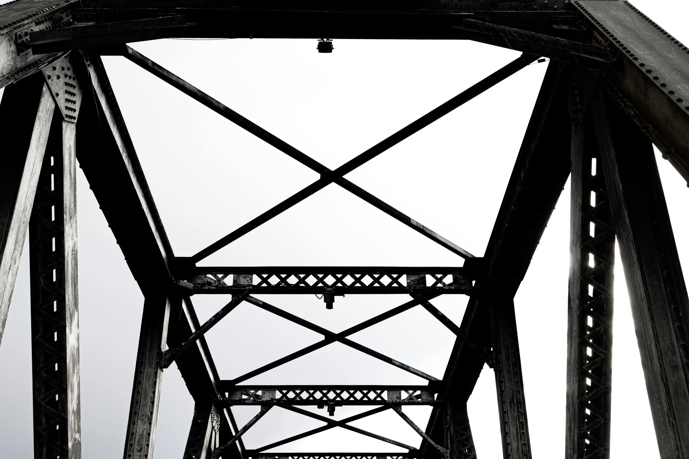 a train bridge spans a highway with a car going underneath it