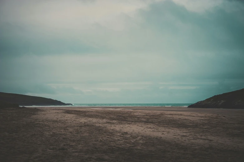 a deserted beach has a cloudy sky, as seen from the distance