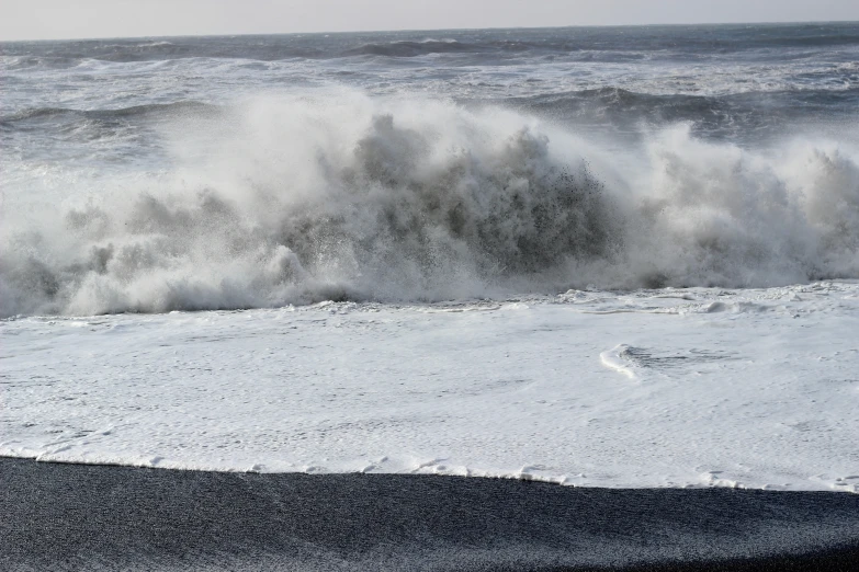 there is a large wave crashing against the beach