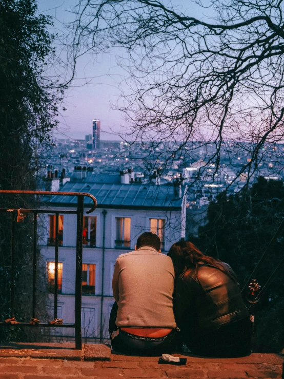 two men sitting on the ledge of a building