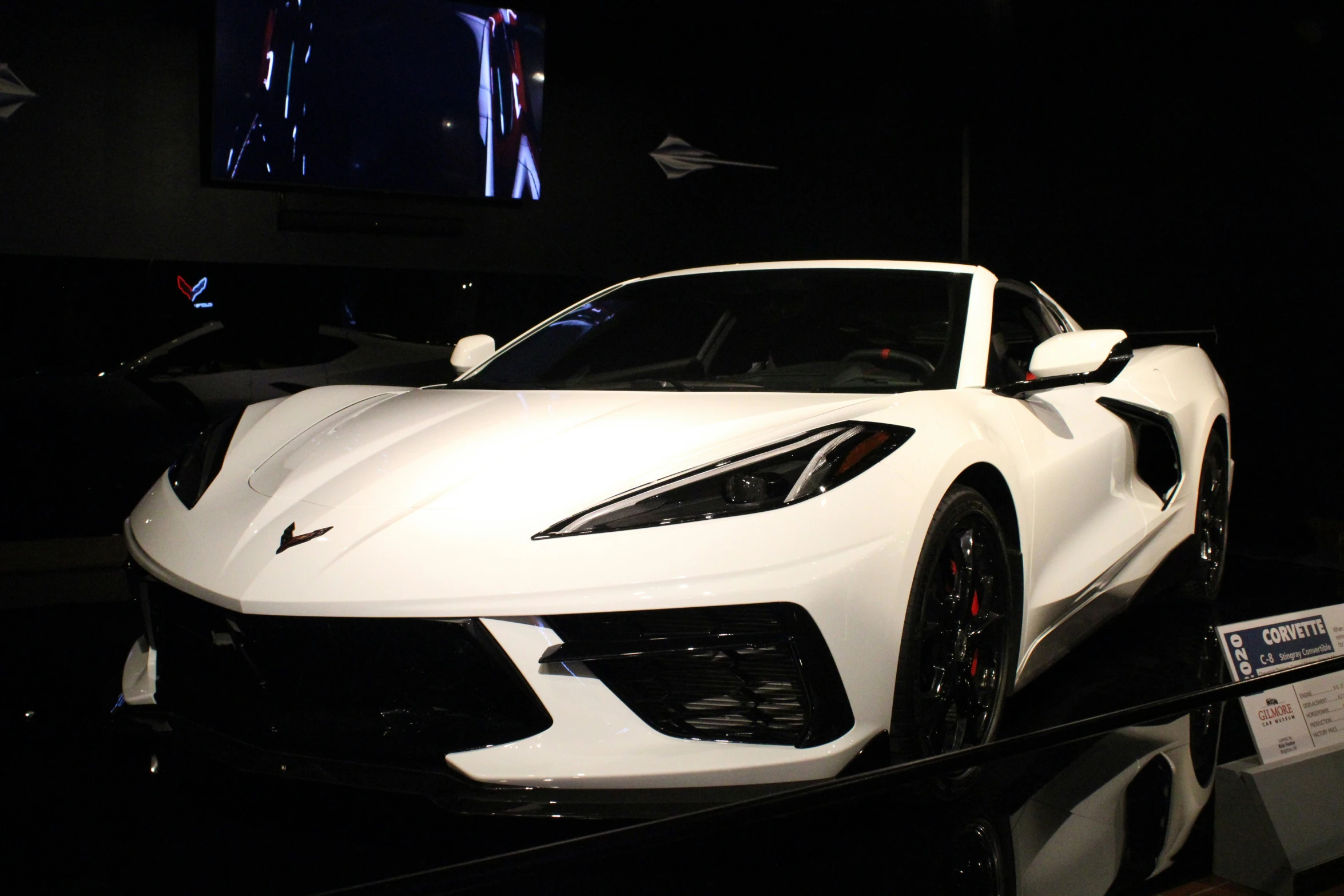 a white sports car sits on a black surface