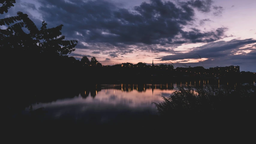 clouds rolling over some trees on a lake